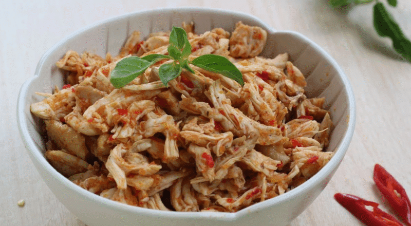 Frango desfiado na panela de pressão, mostrando a textura soltinha da carne.