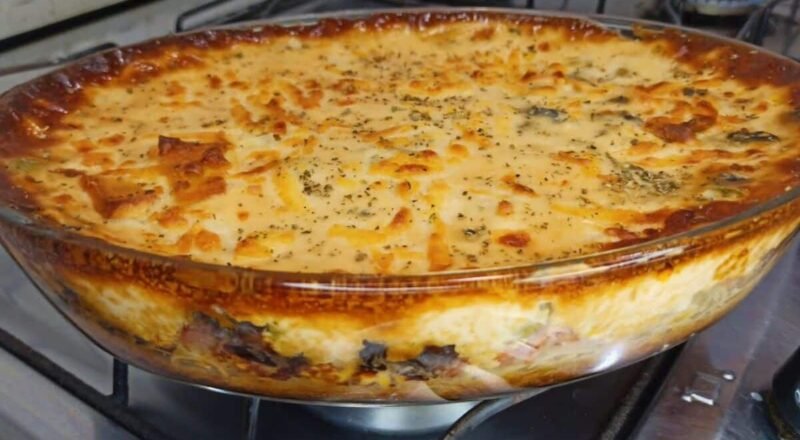 Macarrão de forno cremoso servido em um refratário, com queijo gratinado e ingredientes coloridos como milho e azeitonas.