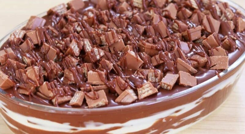 Pavê de KitKat em uma travessa decorada com pedaços de KitKat e fios de ganache