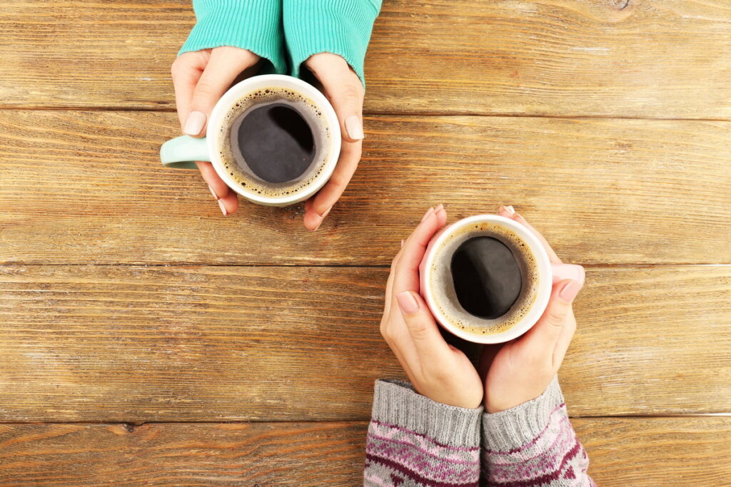 Xícara de café fumegante sobre uma mesa de madeira, representando os benefícios do café para a saúde.