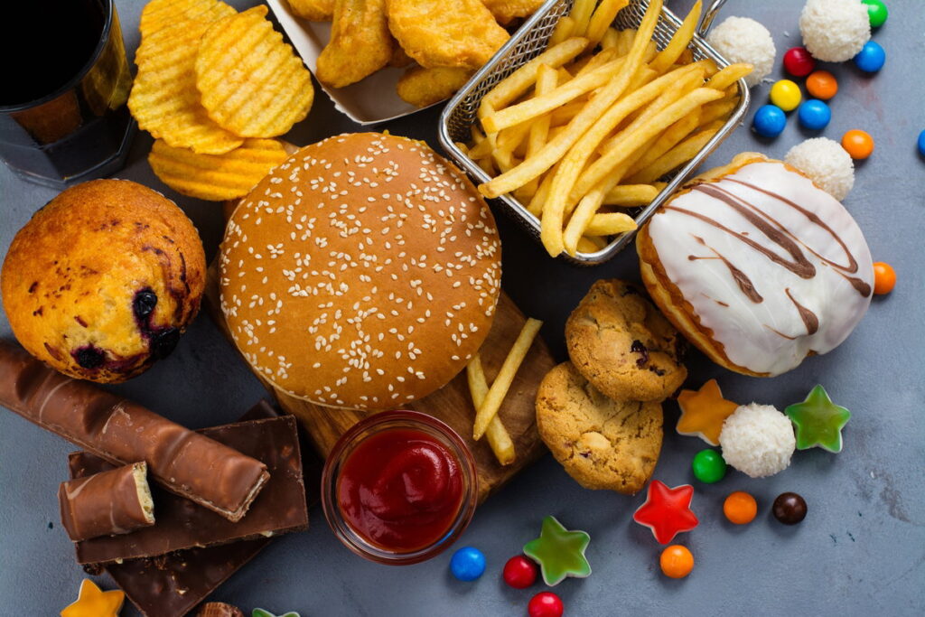 Diversos alimentos ultraprocessados como refrigerantes, biscoitos e fast food em uma mesa