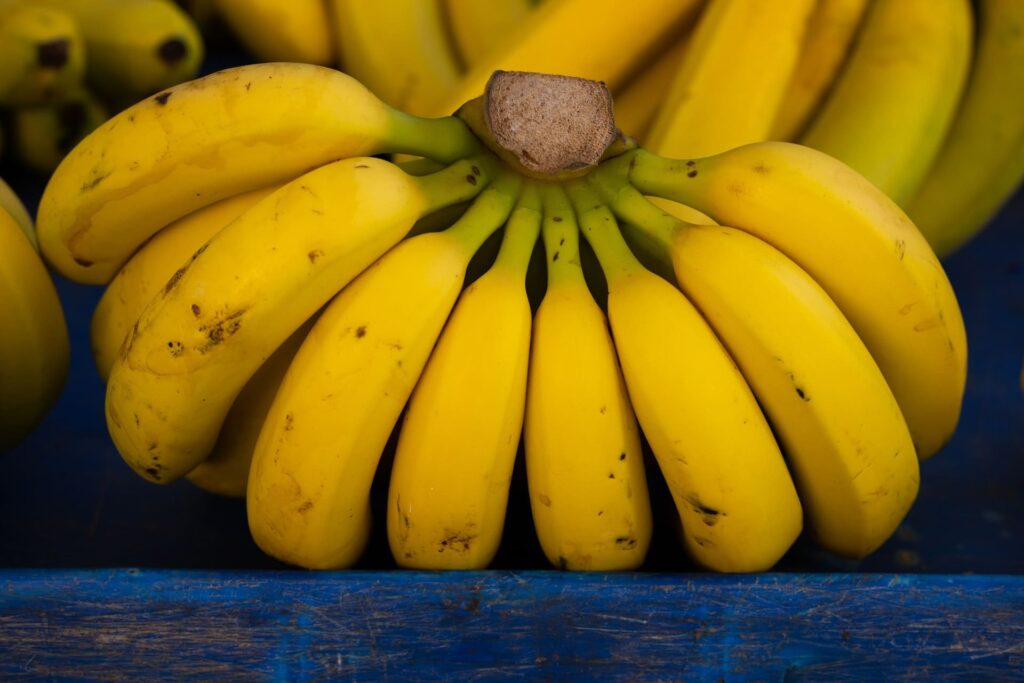 Uma banana madura em cima de uma mesa de madeira, acompanhada de ingredientes para receitas saudáveis.